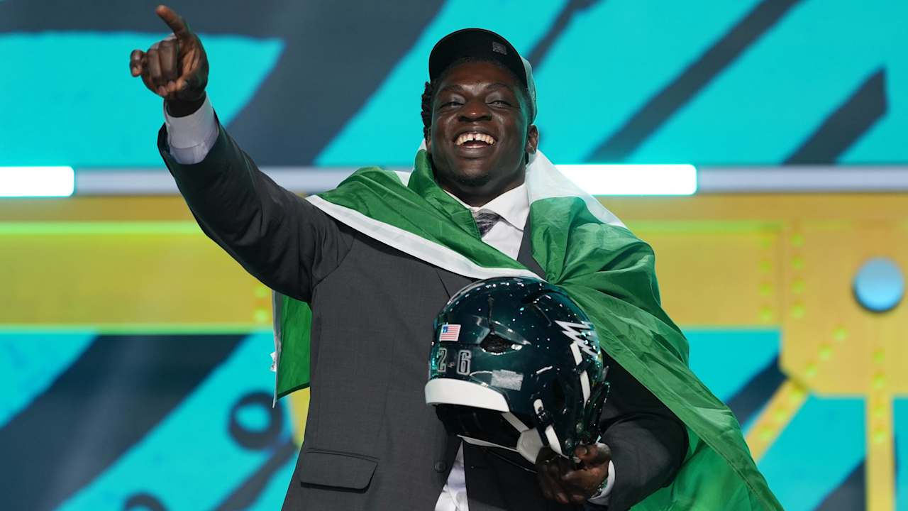 Nigerian defensive tackle Uar Bernard holding a Philadelphia Eagles helmet and wearing the Nigerian flag