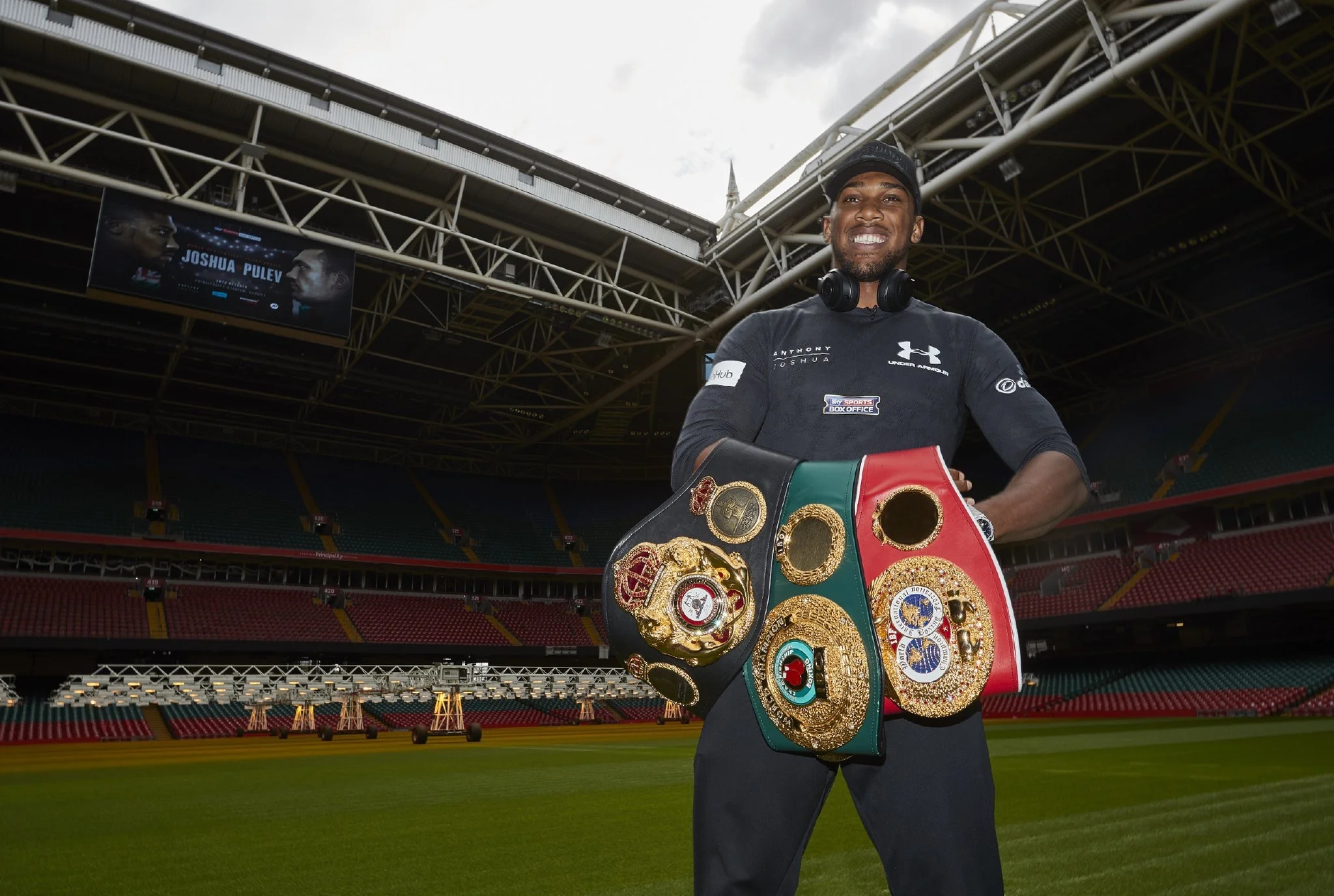 Anthony Joshua posing with heavyweight title belts inside Cardiff’s Principality Stadium