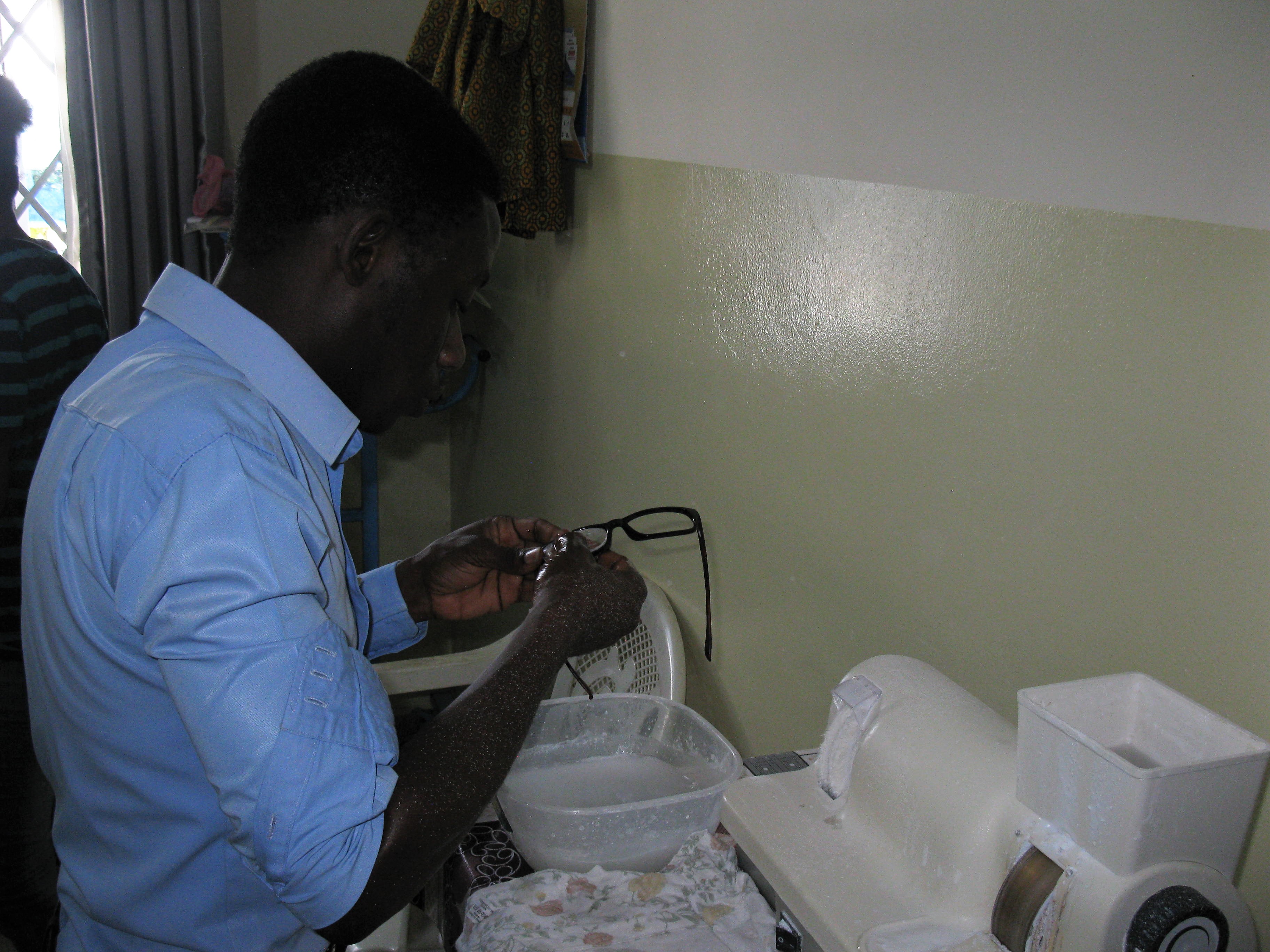 A Ghanaian optician fits a lens into a spectacle frame in 2017; archival image illustrating eye-care services
