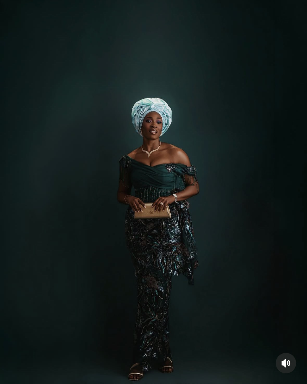 Full-length portrait of Tope Olowoniyan in a dark green outfit and pale blue gele